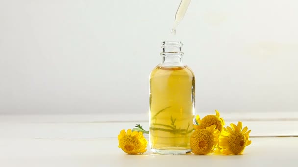 Esencia de flores amarillas de Camomille sobre fondo blanco en hermosa botella de vidrio
 - Imágenes, Vídeo
