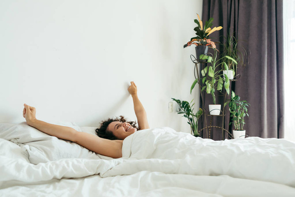 νεαρή όμορφη γυναίκα στο κρεβάτι με λευκά σεντόνια φωτεινό φως - Φωτογραφία, εικόνα