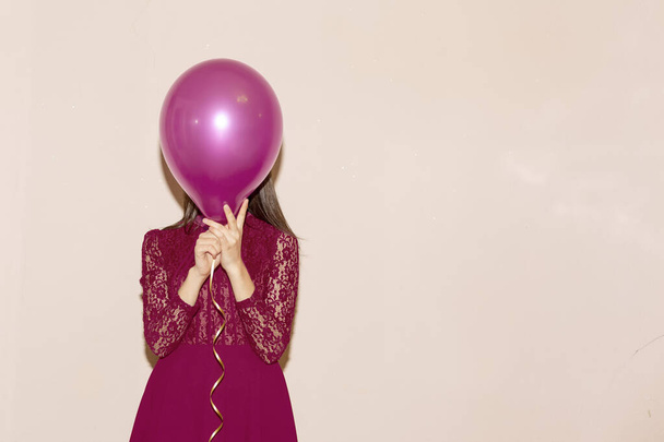 γυναίκα καλύπτει το πρόσωπό της με αερόστατο. Ημέρα του Αγίου Βαλεντίνου, γενέθλια, ημέρα των γυναικών, επέτειος, εορταστική έννοια - Φωτογραφία, εικόνα