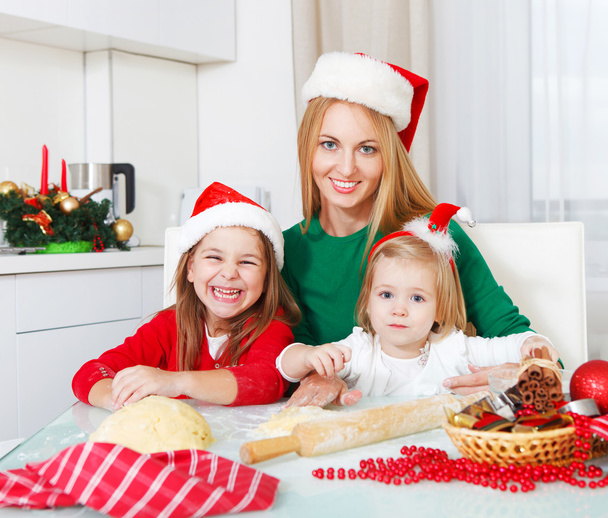 Two girls with mother baking Christmas cookies in the kitchen - Foto, imagen