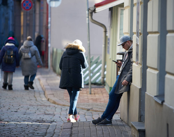12-10-2018 Riga, Letland Jonge knappe man in de stad met smartphone. - Foto, afbeelding