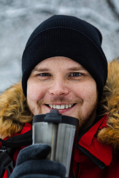 mladý dospělý muž pití kávy z plnitelný hrnek venku - Fotografie, Obrázek