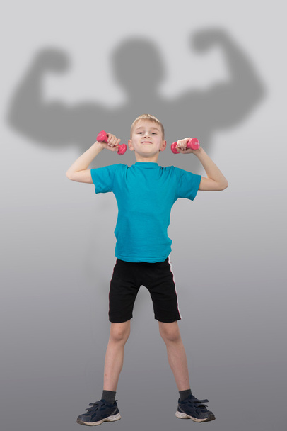 Funny slim boy with bodybuilder's silhouette behind him - Photo, image