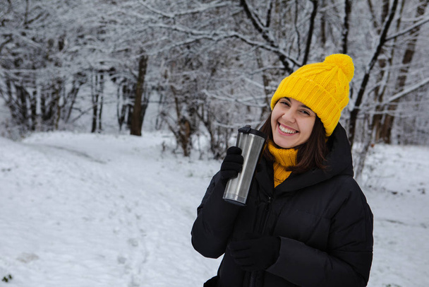 mujer sonriente en traje de invierno beber bebida caliente de taza recargable
 - Foto, Imagen