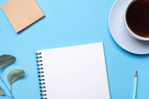 Blue background with notepad, pencil and cup of coffee. - Foto, imagen