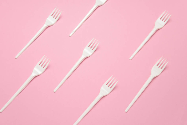 top view white plastic forks pattern on a pastel pink background - Фото, изображение