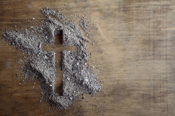 Christian cross symbol made of ash on a wooden background - Fotoğraf, Görsel