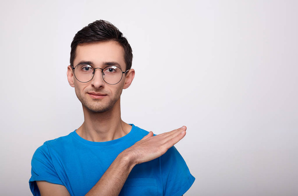 Stylish young man with glasses and a blue T-shirt on a white background. - Photo, Image