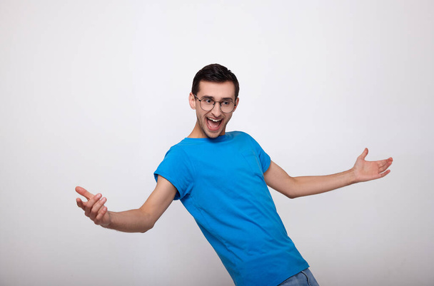 Dancing guy in a blue T-shirt on a gray background. - Photo, Image
