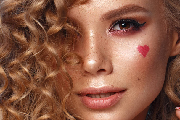 Pretty girl with curls hairstyle, classic makeup, freckles, nude lips and manicure design with hearts. Beauty face. The image for Valentines Day - Photo, Image