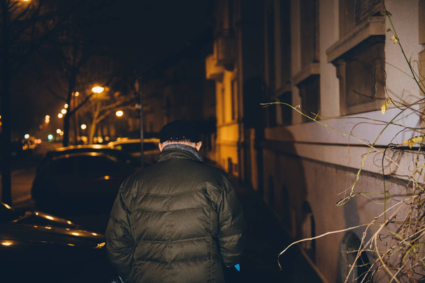 Gece Fransız caddesinde yürüyen yaşlı bir adamın silüetinin üzerine klasik filtre. Mavi teleskopik alüminyum kamış desteği ve rehabilitasyon ile dengeyi koruyan baston kullanarak yürüme. - Fotoğraf, Görsel