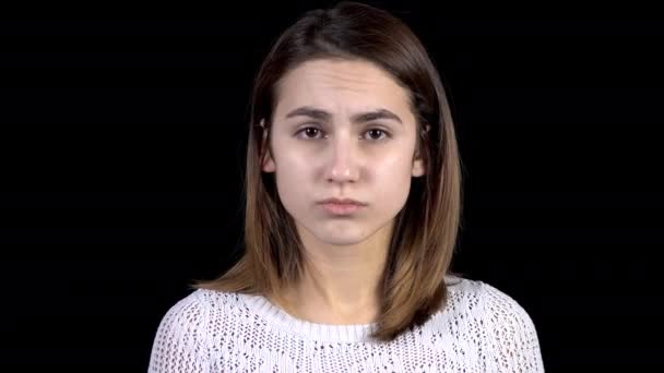 Egy fiatal nő szomorúságot mutat az arcán. A nő szomorú egy fekete háttér közelkép. - Felvétel, videó