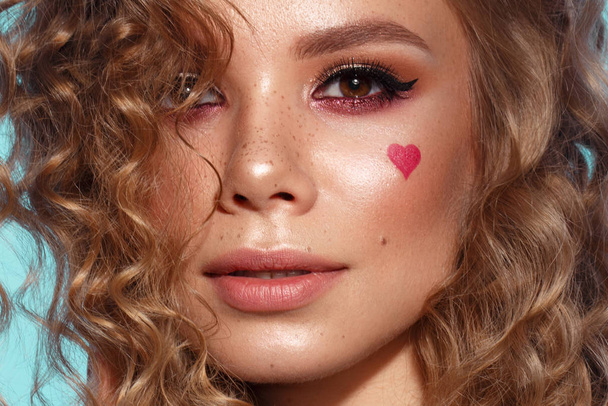 Pretty girl with curls hairstyle, classic makeup, freckles, nude lips and manicure design with hearts. Beauty face. The image for Valentines Day - Zdjęcie, obraz