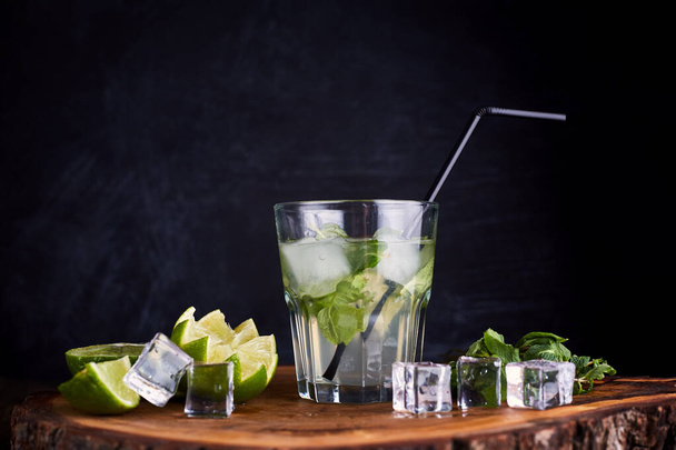 Fresh drink with lime, mint and ice on wooden table on dark background - Foto, imagen