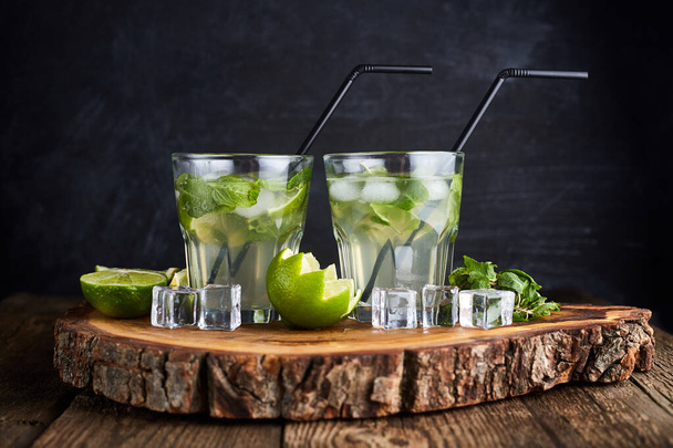 Fresh drink with lime, mint and ice on wooden table on dark background - Foto, imagen