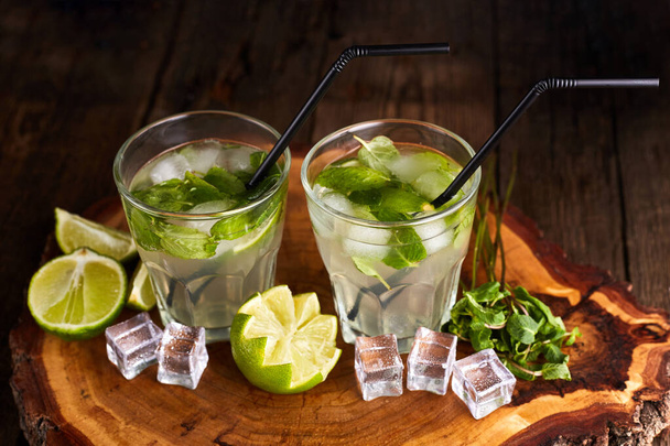 Fresh mojito in glasses with ice cubes on wooden table. - Foto, imagen