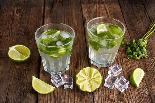 Fresh mojito in glasses with ice cubes on wooden table. - Foto, imagen