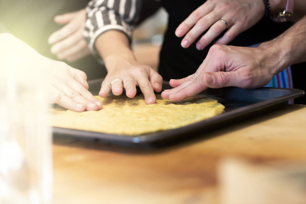 Woman and man teach her friends how to cook food - piza or pie. People cooking at kitchen together. Culinary master class - 写真・画像