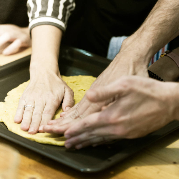 Woman and man teach her friends how to cook food - piza or pie. People cooking at kitchen together. Culinary master class - Foto, imagen