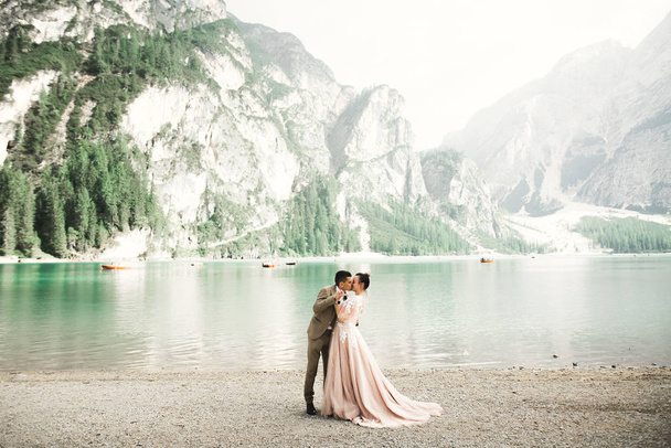 Casal jovem perto de um belo lago nas montanhas. Amantes se amam bem e sorriem - Foto, Imagem