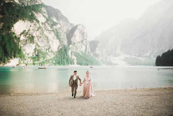 Young couple near lake Lago Di Braies, Italy. Holding hands at the stone at lake - Foto, Bild