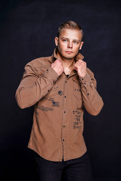 man in a brown shirt on a black background - Foto, afbeelding