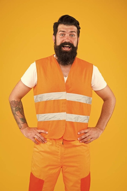 Safety apparel for construction industry. Bearded brutal hipster safety engineer. High visibility reflective safety vest. Man worker protective uniform orange background. Safety equipment concept - Фото, зображення