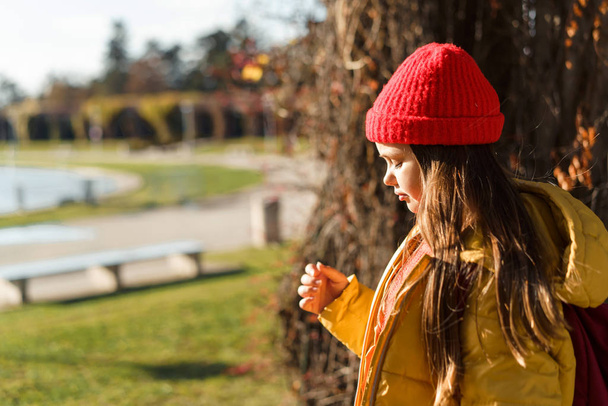 Girl with blond long hair in a knitted red hat and yellow jacket - 写真・画像