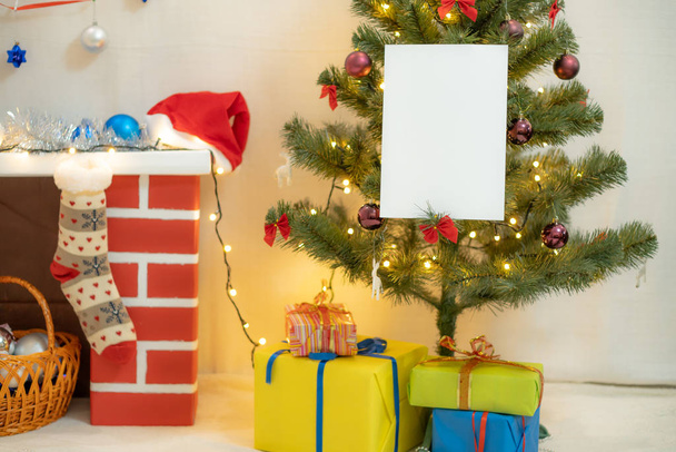 White blank sheet of paper against the background of the Christmas tree and the fireplace - Foto, imagen