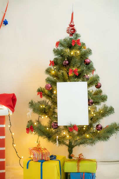 Wit blanco vel papier tegen de achtergrond van de kerstboom en de open haard - Foto, afbeelding