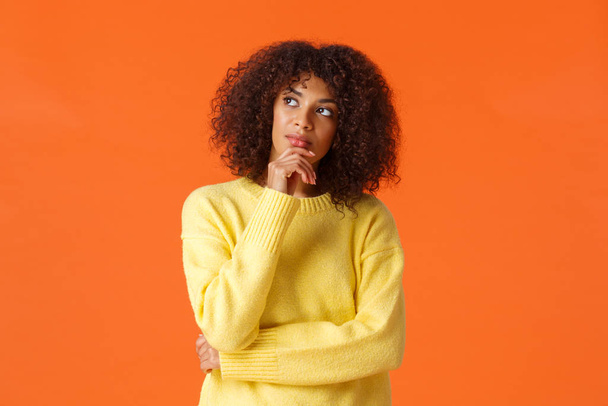 Waist-up portrait unsure, thoughtful young creative african-american female entrepreneur making new ideas, standing orange background, searching inspiration, thinking looking up - Fotoğraf, Görsel