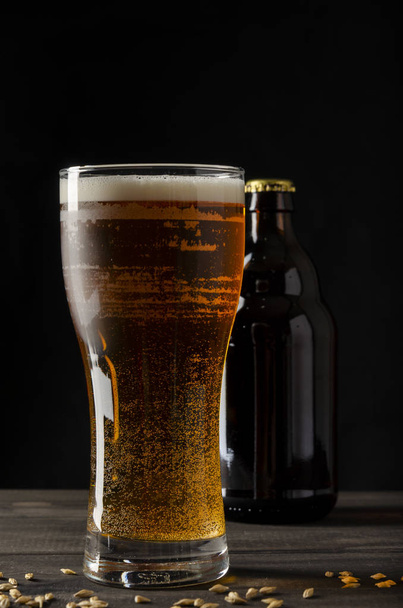beer bottle on black background with glass of beer - Фото, зображення