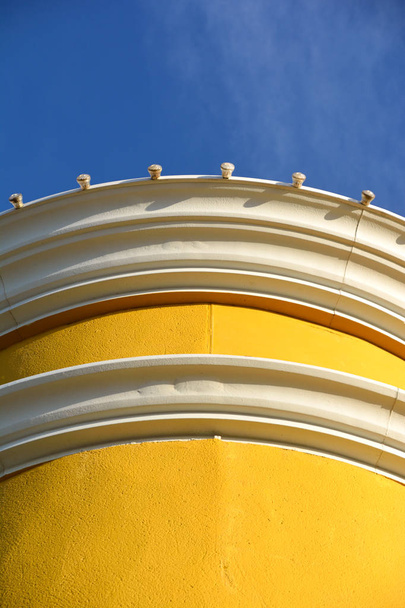 Detailaufnahme der Spitze eines gelben Gebäudes vor blauem Himmel - Foto, Bild