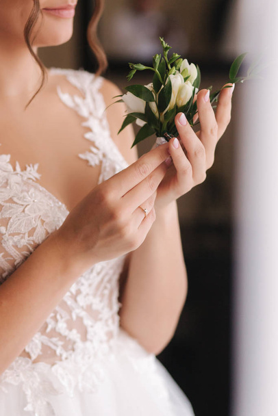 Close up of bride hold in hands boutonniere for groom - Фото, изображение