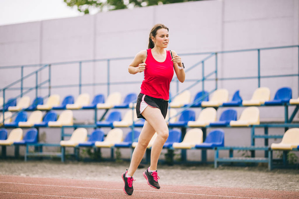 Жінка біжить на трасі стадіону, спортсменка бігає і працює на відкритому повітрі, спорт і фітнес-концепція. Молода жінка в спортивному одязі тренується на стадіоні. Тема спортивного способу життя
 - Фото, зображення
