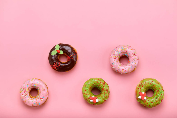 Donuts multicolores sobre un fondo rosa doblado en una forma geométrica
. - Foto, imagen