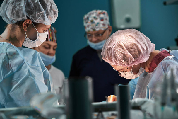 Grupo de cirujanos en quirófano. Equipo médico realizando cirugía en quirófano
. - Foto, Imagen