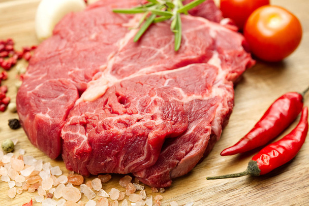 Syrové hovězí steaky na dřevěné desce shora. čerstvý steak s kořením připraveným na vaření. - Fotografie, Obrázek