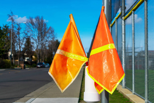 Jasnopomarańczowy pieszy przekraczania flagi na przejściu granicznym w dzielnicy mieszkalnej w pobliżu szkoły - Zdjęcie, obraz