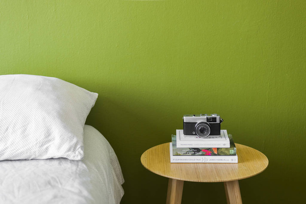 Ágymelletti asztal könyvekkel és fényképezőgéppel - Fotó, kép