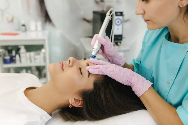Közelkép egy nőről, aki arcvíz- mikrodermabráziós kezelést kap. Nő kozmetikai szépségszalonban. Hidra porszívó. Kozmetológia - Fotó, kép