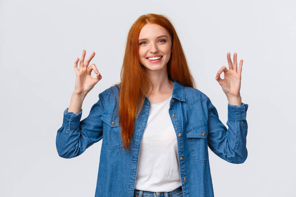 Waist-up portrait modern good-looking redhead girl in casual shirt, showing okay gestures and smiling, nod in approval, agreement, rate good movie, perfect service, stand white background - Foto, afbeelding
