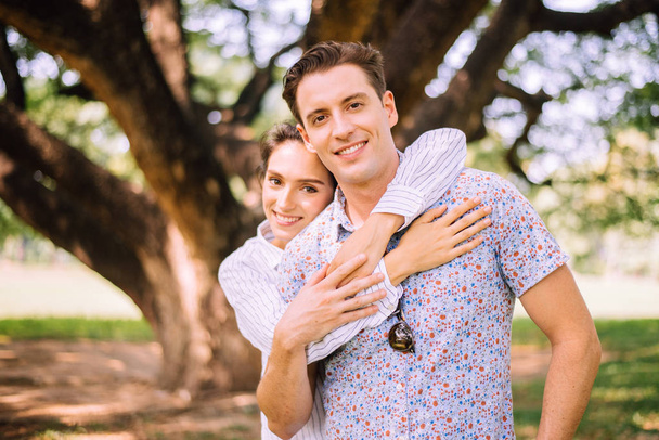 Ζευγάρι νέοι ερωτευμένοι αγκαλιασμένοι στο πάρκο, ρομαντικοί και απολαμβάνοντας τη στιγμή της ευτυχίας, ευτυχισμένοι και χαμογελαστοί, θετική σκέψη - Φωτογραφία, εικόνα