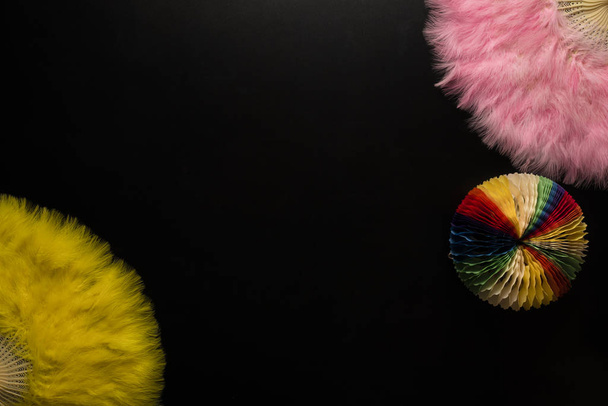 Objetos de carnaval sobre fondo negro. Abanicos chinos rosados y amarillos, objeto estrella de papel
 - Foto, Imagen
