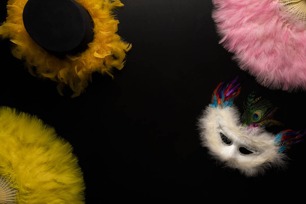 Objetos de carnaval sobre fondo negro. Abanicos chinos, sombrero, serpentinas en espiral, máscaras, confeti
 - Foto, Imagen