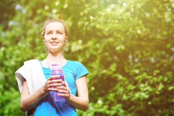 Fitness woman drinking water after running training in summer park - Foto, Imagen