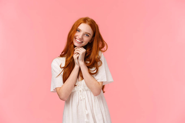 Cuteness overload. Silly kawaii redhead european girl with lovely gaze and grin, tilt head, begging something, asking buy cute thing in store, smiling cheerful, standing pink background - 写真・画像