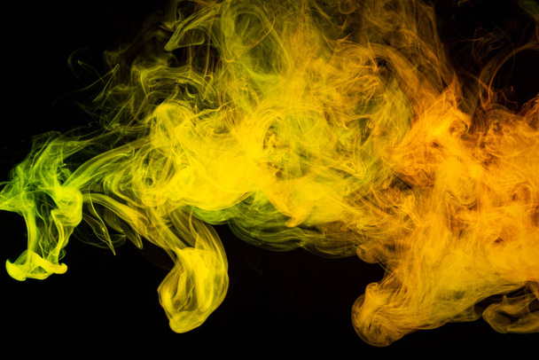 Cloud of  yellow and orange  smoke on a black isolated background. Background from the smoke of vape - Photo, Image