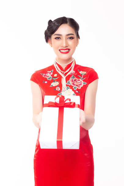 Kaunis nuori aasialainen nainen antaa lahjan kiinalainen uusivuosi. Viehättävä kaunis tyttö saada onnea, kun antaa lahjan perheelle, ystävä. Hänellä on hieno kiinalainen mekko. Hänellä on lahjapakkaus. Syntymäpäivälahja
 - Valokuva, kuva
