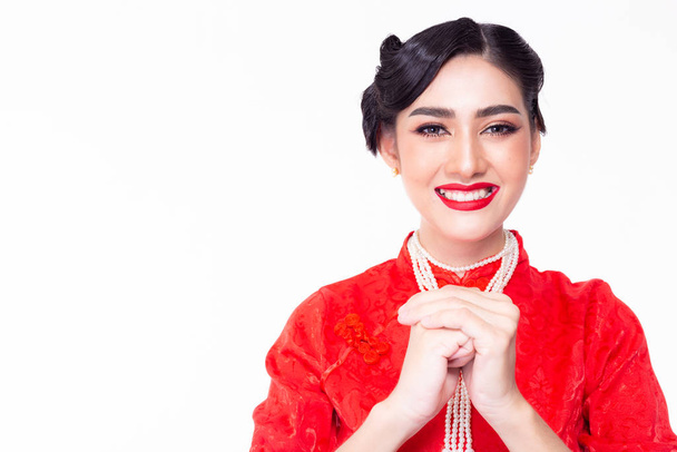 Krásná Číňanka zdraví někoho v čínském Novém roce. Hezká asijská žena je požehnání, přeje lidem získat prosperitu, štěstí, štěstí v Číně Nový rok Atraktivní mladá dívka nosí cheongsam - Fotografie, Obrázek